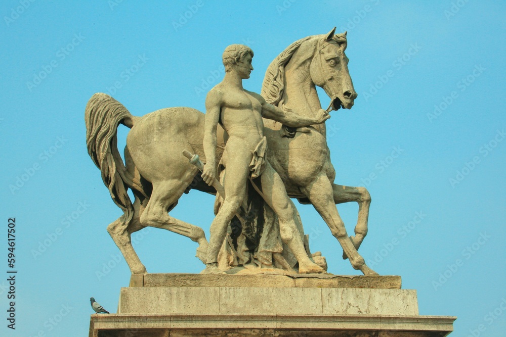 Large ornate statue of a man with horse in Paris, with the clear blue sky in background