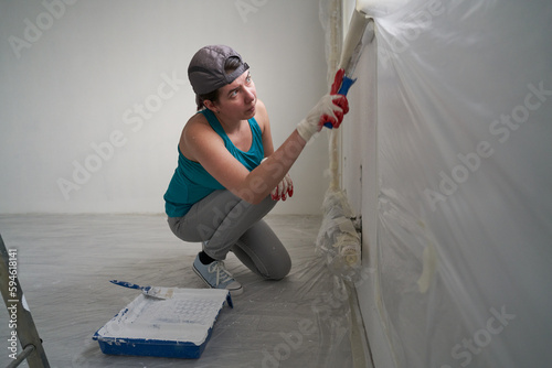 Fotografia Woman paints the wall with a roller