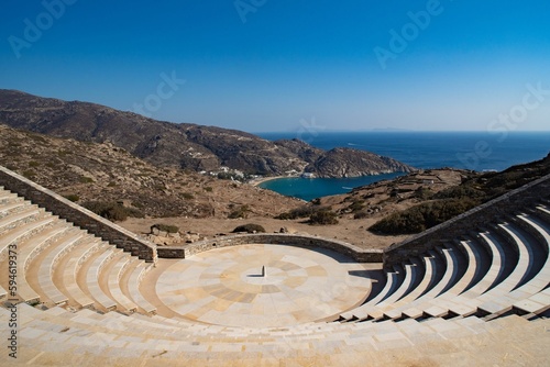Ancient Greek theatre, standing on a rocky hillside overlooking a tranquil lake
