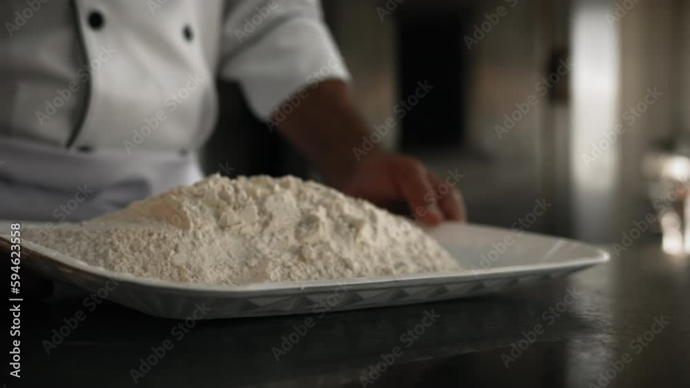 Professional Man preparing flour on a white tray to make bread dough on a table Professional Man preparing flour on a white tray to make bread dough on a table