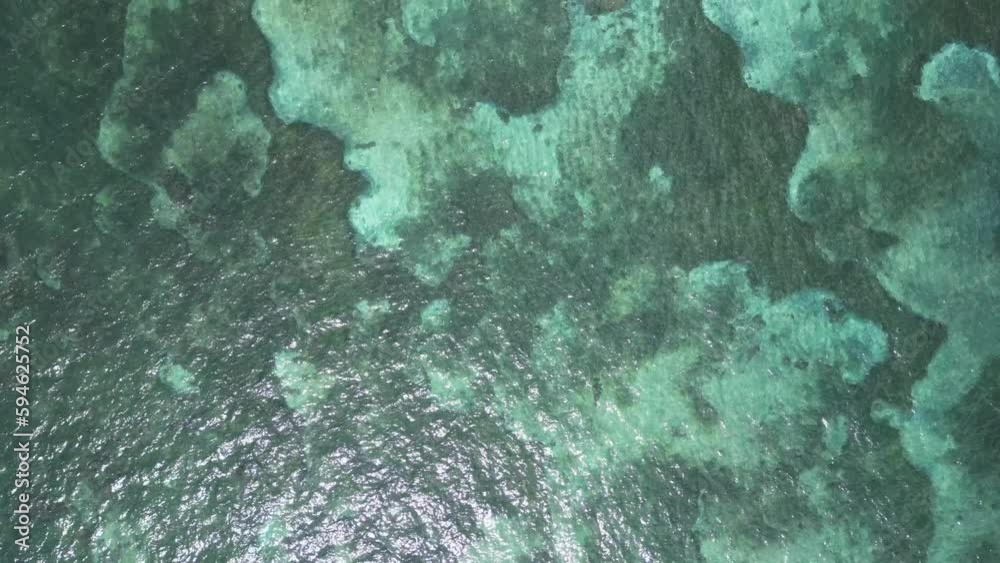 Top down aerial view of green ocean water over reef and sand bar by reef Top down aerial view of green ocean water over reef and sand bar by reef