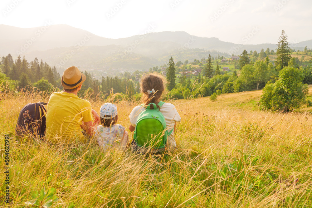 Happy young family sitting back view mountain family nature vacation green travel together nature child mountain kid parents child landscape kid. Green weekend family looking at mountain travel nature
