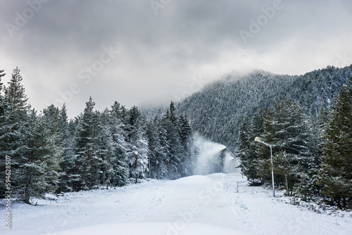 Ski slope preparation in winter bulgarian mountains. Snow cannons spraying artificial snow. Bansko ski resort, Bulgaria.