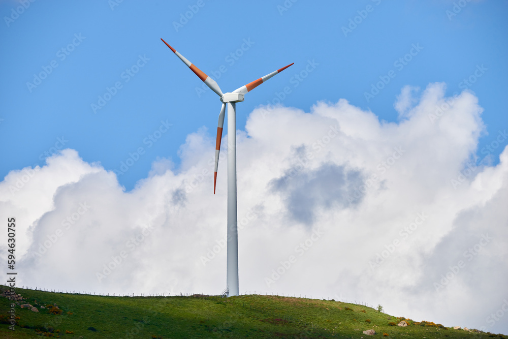 Fototapeta premium wind turbines among the green hill pastures in the clouds and wind of spring
