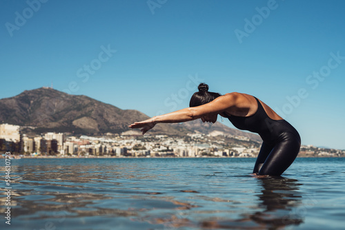 a girl swimmer in a black jumpsuit is swimming in the sea warming up doing exercises for swimming