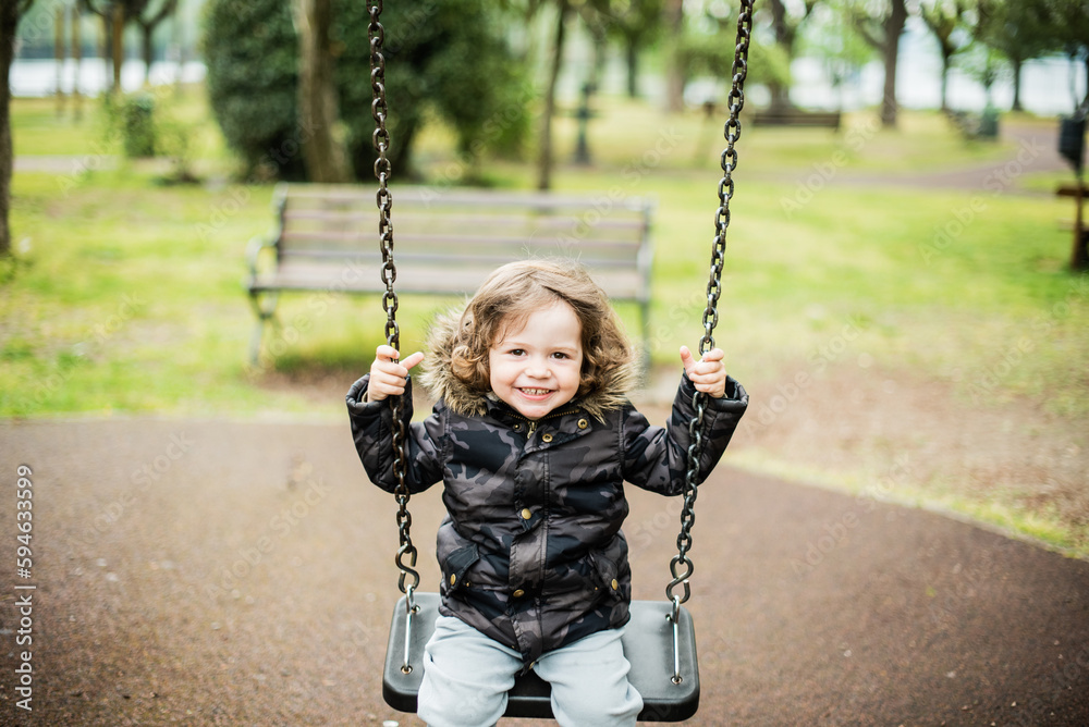 child plays on the public playground, has fun on the swing and laughs in amusement