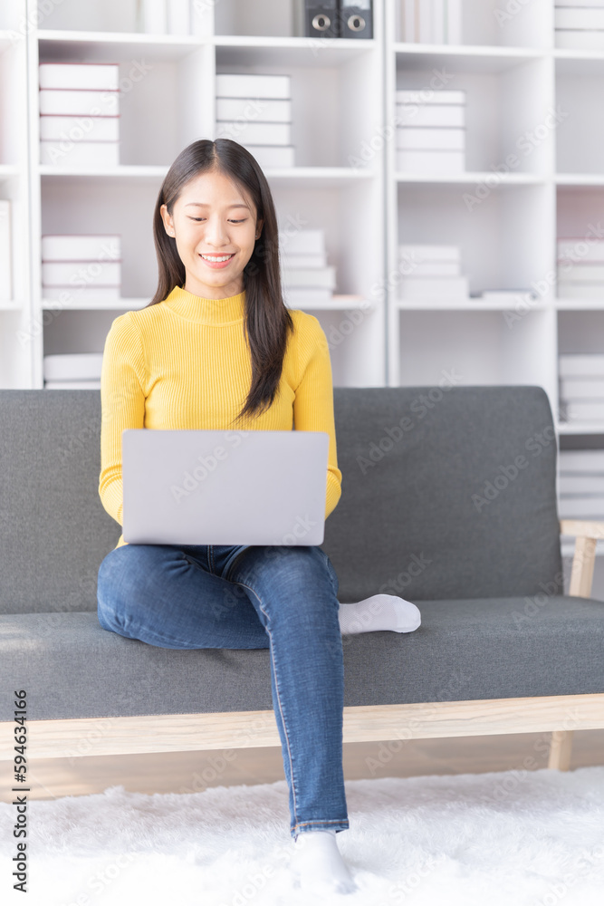 Young Asian woman sitting on sofa holding Teacup and notebook and check email, in the leaving room. Young Asian woman sitting on sofa holding Teacup and notebook and check email, in the leaving room.