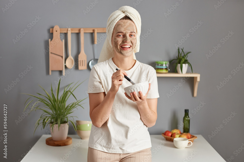 Beautiful caucasian smiling young woman posing in kitchen with towel on head making cosmetology procedures skin care treatment lazy beauty morning. Beautiful caucasian smiling young woman posing in kitchen with towel on head making cosmetology procedures skin care treatment lazy beauty morning.