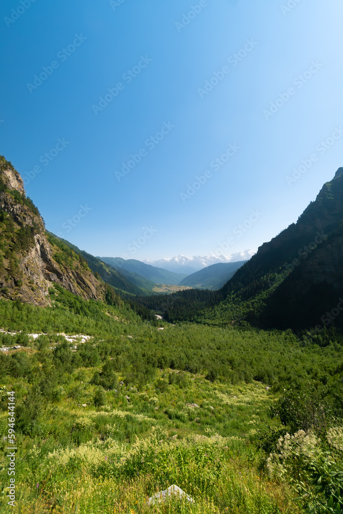 Beautiful mountain landscape on the valley near the waterfall Shdugra, Mazeri, Svaneti, Georgia on a sunny bright summer day. Vertical photo
