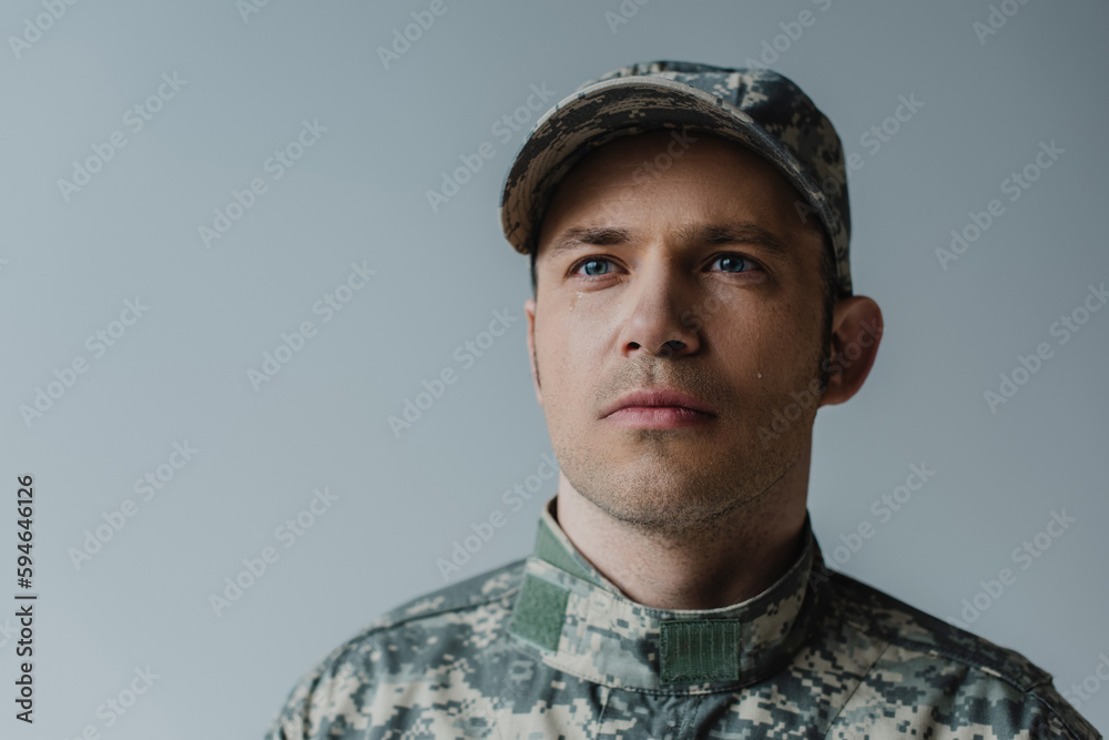 sad military man in uniform crying during memorial day isolated on grey.