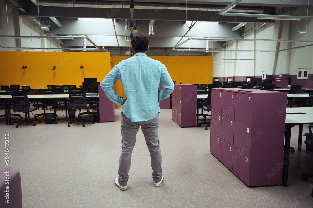 Man standing in office and looking for place to work Man standing in office and looking for place to work