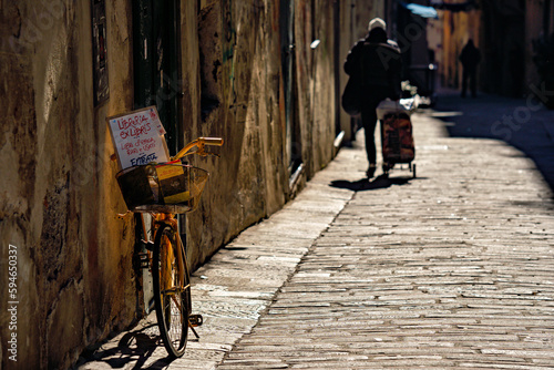 einsames Fahrrad an Häuserwand bei Straße mit Tropfsteinpflaster in Italien
