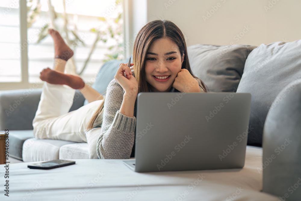 Young woman relaxing using laptop computer on a cold winter day in the bedroom. woman checking social apps and working. Communication and technology concept Young woman relaxing using laptop computer on a cold winter day in the bedroom. woman checking social apps and working. Communication and technology concept