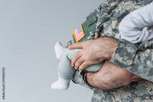 Fototapet cropped view of American serviceman in uniform holding newborn baby isolated on grey