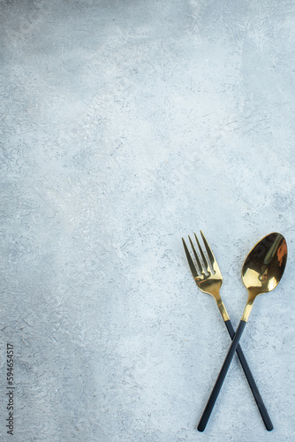 Elegant cutlery set on the left side on gray background with distressed surface with free space