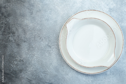 Empty white soup plates on the left side on half dark light gray background with distressed surface with free space