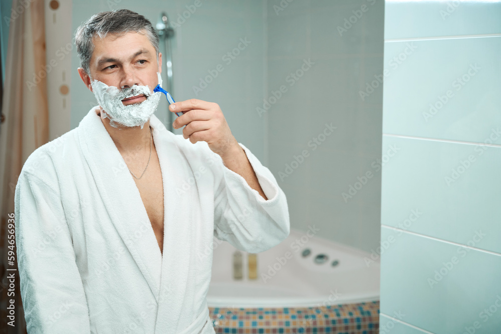 Man shaving in shower in the hostel Man shaving in shower in the hostel