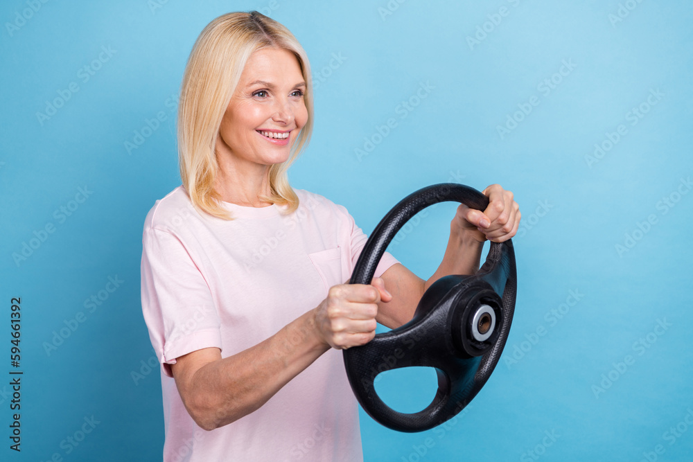 Portrait of positive woman straight hairdo wear white t-shirt hold steering wheel look empty space isolated on blue color background Portrait of positive woman straight hairdo wear white t-shirt hold steering wheel look empty space isolated on blue color background
