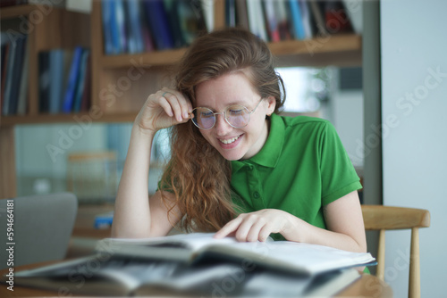 Happy girl, young woman read book in library, college or university student prepare to exam in glasses and smile