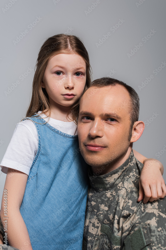 patriotic kid hugging serviceman in army uniform and crying during memorial day isolated on grey.