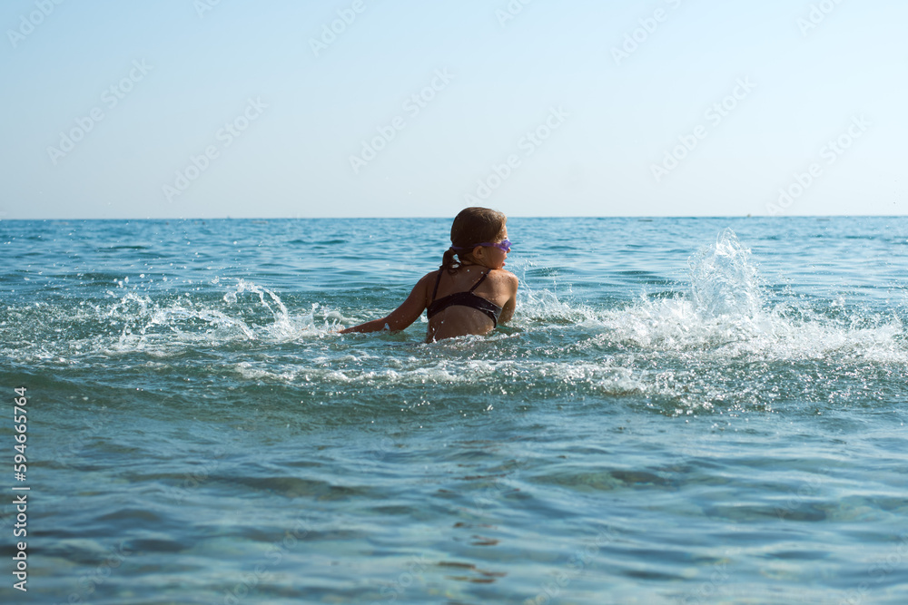 child splashing water, bathing at the sea on vacations, having fun child splashing water, bathing at the sea on vacations, having fun