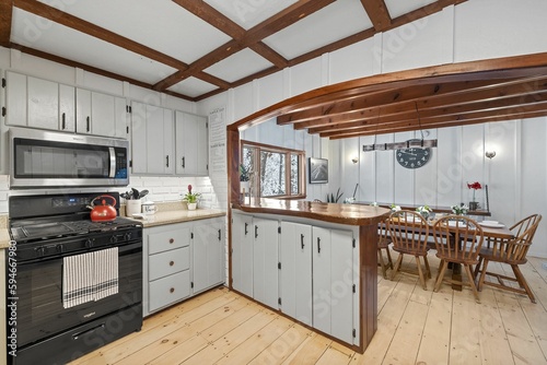 a kitchen with wood floors and ceiling beams next to an oven © Allan Wolf/Wirestock Creators