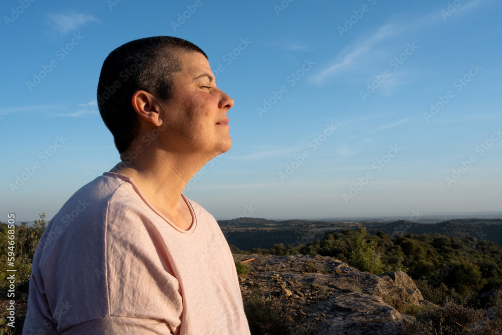 profile portrait of a woman with short hair, eyes closed, taking in the last rays of daylight, relaxed in the middle of nature, very white skin, reddish with sun spots on the skin. profile portrait of a woman with short hair, eyes closed, taking in the last rays of daylight, relaxed in the middle of nature, very white skin, reddish with sun spots on the skin.