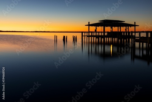Calm sunrise over a wooden structure on on the water on a misty morning
