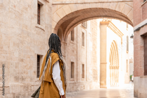 a woman with braids walks through the streets of Valencia in Spain.