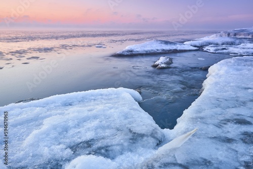 Idyllic frozen rocky shore with pink sky on the horizon, perfect for wallpapers