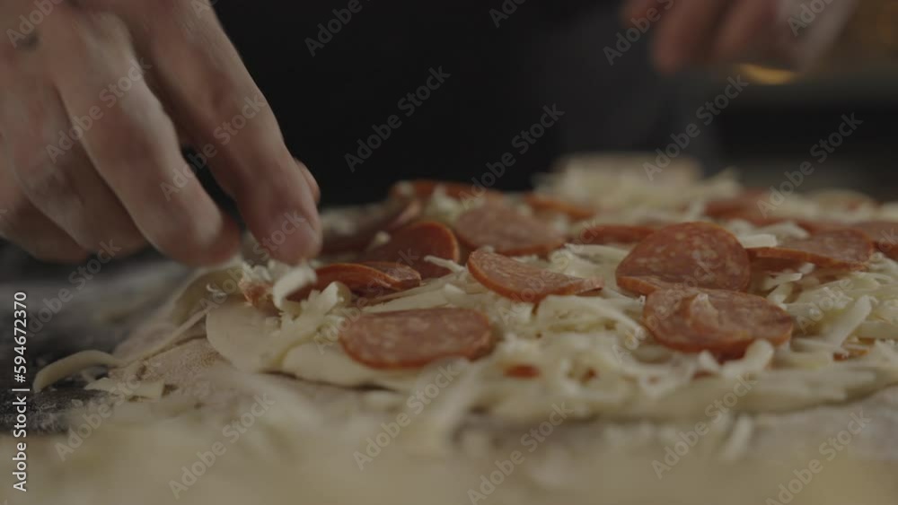 Close-up slow-motion view of a person preparing homemade pepperoni pizza in a kitchen Close-up slow-motion view of a person preparing homemade pepperoni pizza in a kitchen
