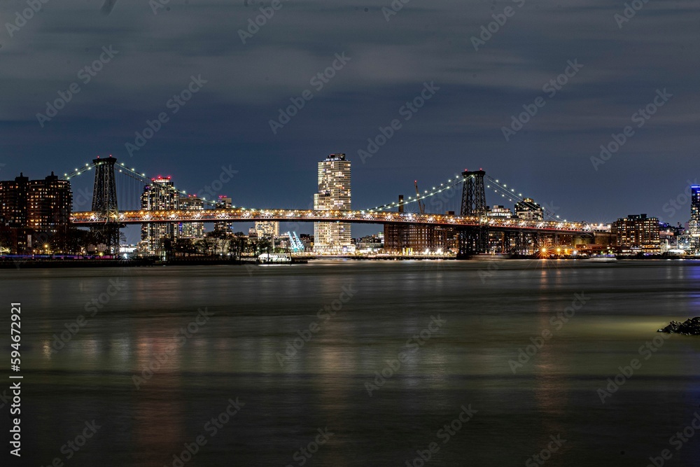 Brooklyn Bridge illuminated with lights at night on the background of the modern cityscape