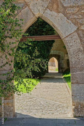a stone archway in the middle of a walkway leading to a garden
