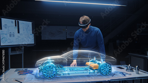 Automotive Engineer Wearing VR Headset Working on 3D Electric Car Prototype, Using Gestures in Augmented Reality. Designs and Manipulates Graphical Parts, Picks Body for the Chassis and Engine photo