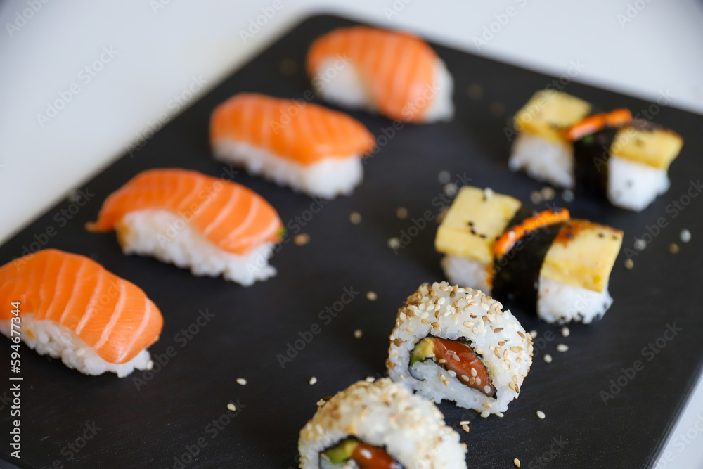 close up of sushi set on dark tray close up of sushi set on dark tray