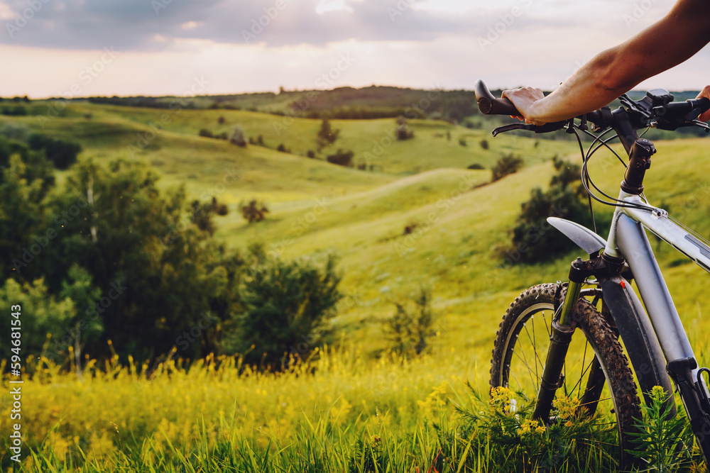 Obraz premium Young man with bicycle on a rural road enjoying sunset