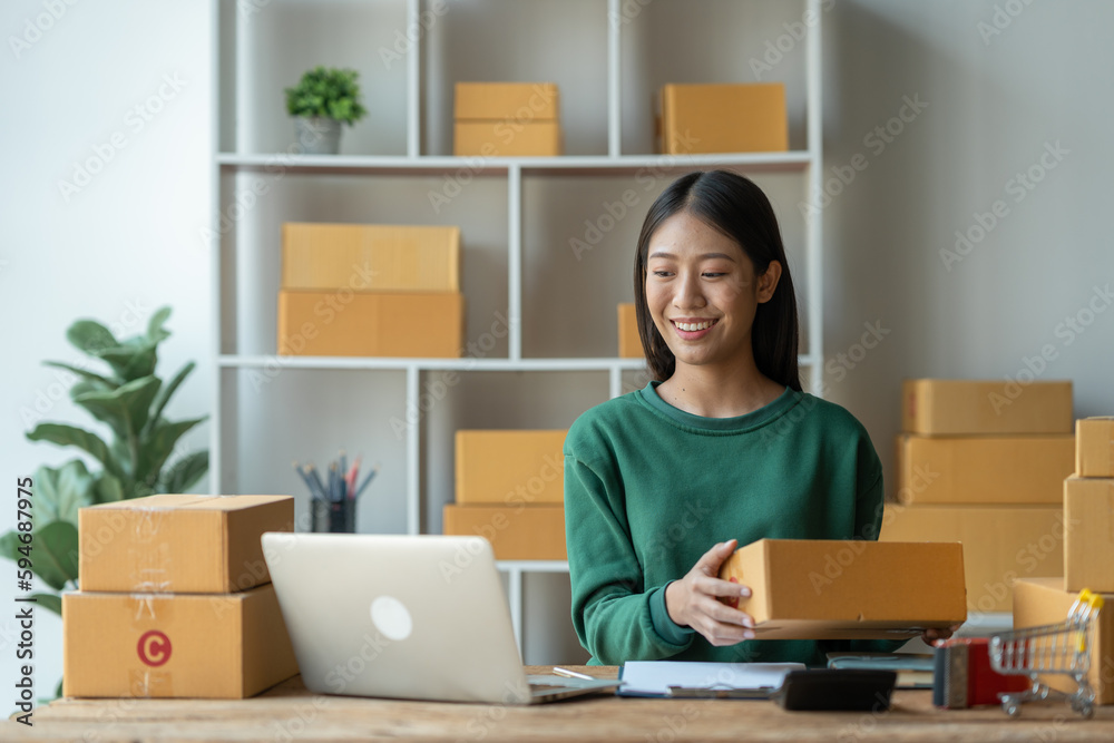 Asian female startup business owner She smiled and was delighted to receive an online order from a customer showing her information on her laptop to prepare parcels for delivery through the company. Asian female startup business owner She smiled and was delighted to receive an online order from a customer showing her information on her laptop to prepare parcels for delivery through the company.