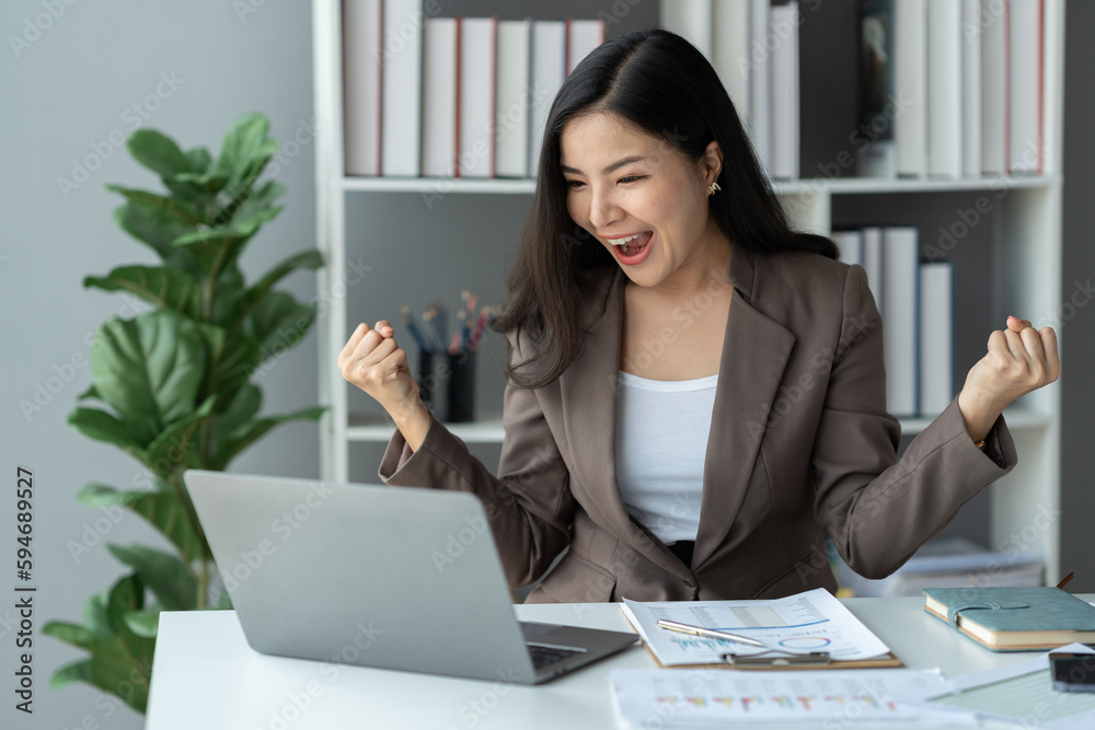 Asian businesswoman, investor showing a happy expression to know the results of financial approval Revenue that has been agreed in the business of real estate projects on a laptop computer in office. Asian businesswoman, investor showing a happy expression to know the results of financial approval Revenue that has been agreed in the business of real estate projects on a laptop computer in office.