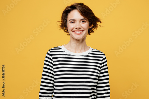Young smiling happy fun cheerful satisfied positive european woman wear casual striped black and white shirt looking camera isolated on plain yellow color background studio portrait Lifestyle concept