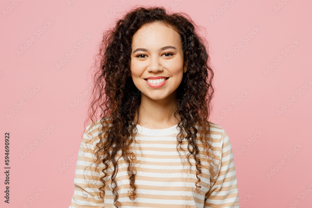 Young cheerful happy fun satisfied cool woman of African American ethnicity she wearing light casual clothes looking camera with toothy smile isolated on plain pastel pink background studio portrait. Young cheerful happy fun satisfied cool woman of African American ethnicity she wearing light casual clothes looking camera with toothy smile isolated on plain pastel pink background studio portrait.