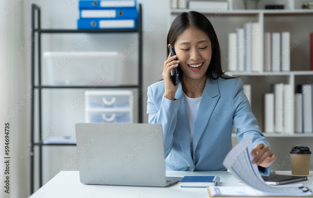 Asian businesswoman using mobile phone Laptop computer in private office to communicate through online applications and happy smile startup business ideas. Asian businesswoman using mobile phone Laptop computer in private office to communicate through online applications and happy smile startup business ideas.