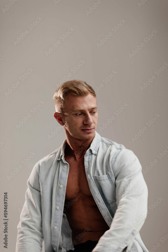 Obraz premium fair-haired male bodybuilder in a blue shirt in the studio.