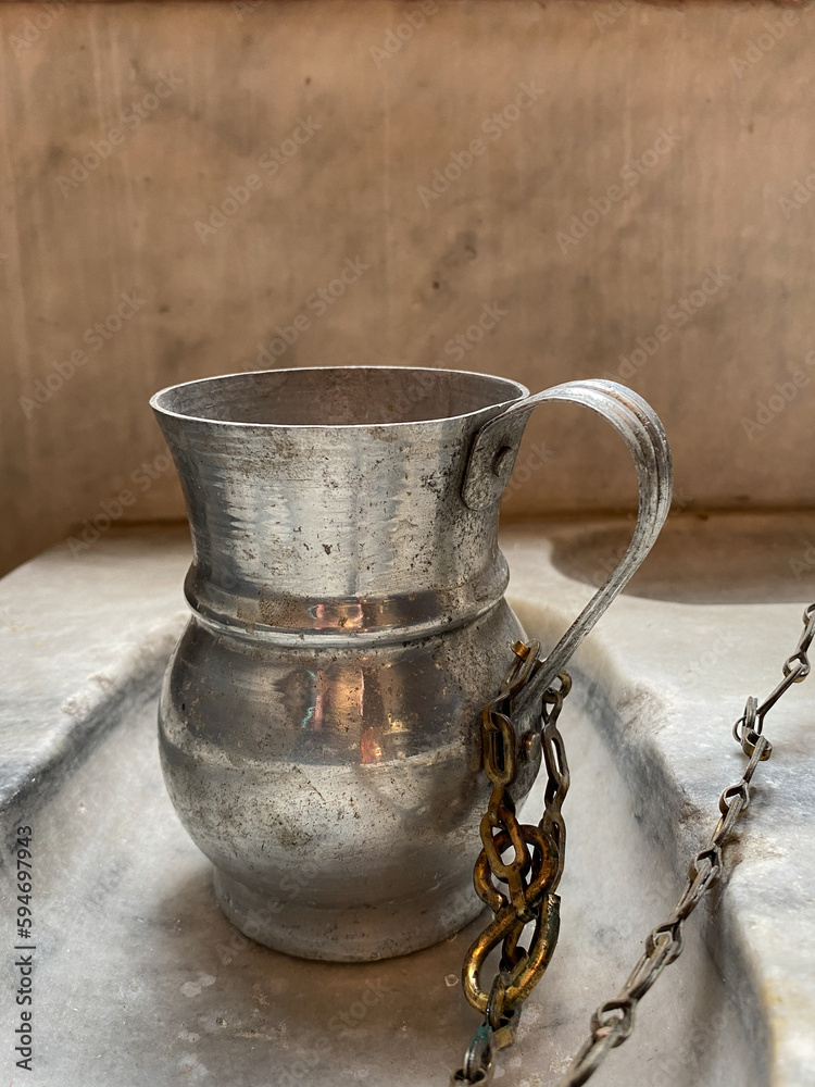 Traditional pewter tankard chained to marble counter in orthodox church Traditional pewter tankard chained to marble counter in orthodox church
