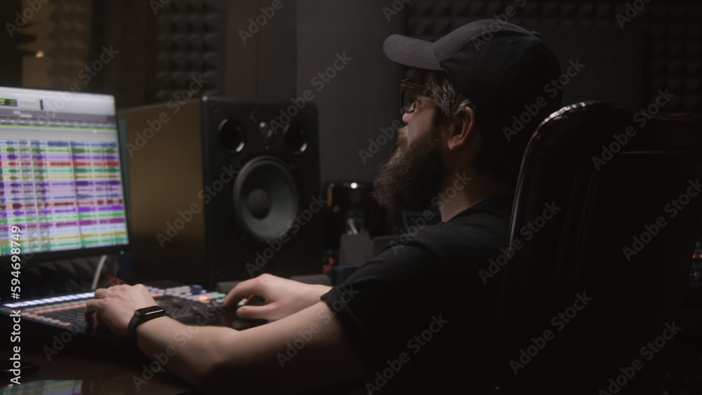 Experienced audio engineer uses mixing board to create new song sound in audio recording studio. Program and tools on computer monitor. Digital audio workstation software. Concept of music production. Experienced audio engineer uses mixing board to create new song sound in audio recording studio. Program and tools on computer monitor. Digital audio workstation software. Concept of music production.