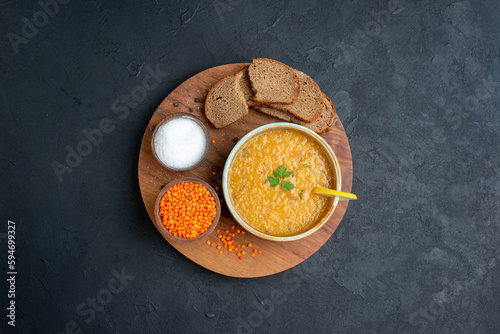 Φωτογραφία top view lentil soup with salt raw lentils and dark bread loafs on dark surface