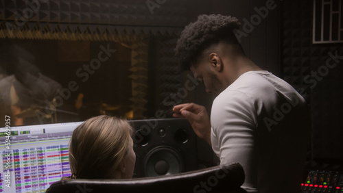 Photos Experienced audio engineer and African American producer work with singer in sound recording studio