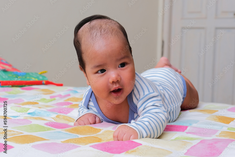 Asian infant showing happy face expression when doing tummy time Asian infant showing happy face expression when doing tummy time
