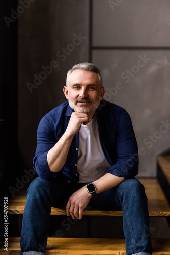 Mature middle age man sitting on stairs at home