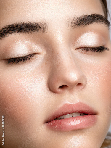 Attractive young woman face closeup with neutral make up and healthy clear skin. Beauty portrait. Salon skin care and cosmetology occupation.