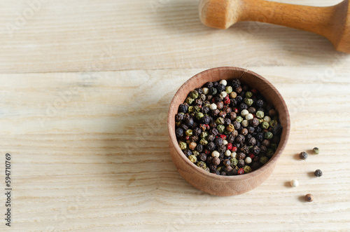 Fototapeta Naklejka Na Ścianę i Meble -  Mix peppercorns black, white, red and allspice in a wooden pestle with a chime for a mortar on a wooden background. dried spice peppercorn concept. Horizontal orientation. Selective focus. Copy space.